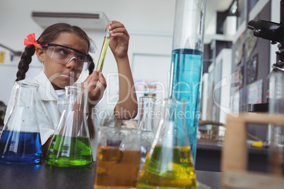 Elementary student examining yellow chemical in test tube at laboratory