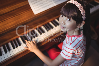 High angle portrait of girl practicing piano in classroom