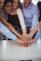 Happy business colleagues stacking their hands on desk