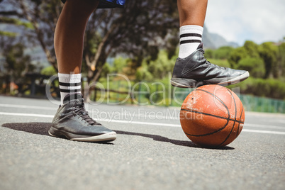 Close up of man standing with one leg on basketball