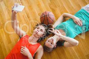 Overhead view of playful friends taking selfie while lying on floor
