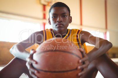 Close up portrait of teenage boy with ball sitting on floor