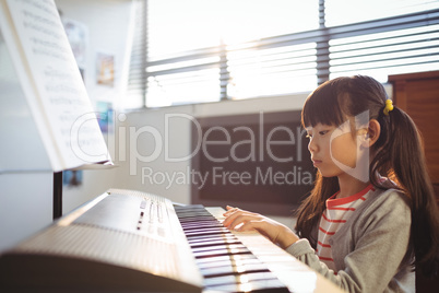 Concentrated girl practicing piano in class