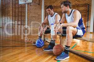 Male basketball players talking while sitting on bench