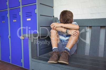Full length of boy sitting on bench by lockers
