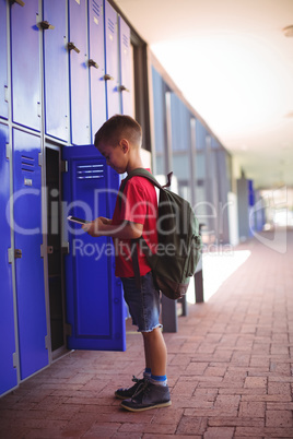 Side view of boy using mobile phone by open locker