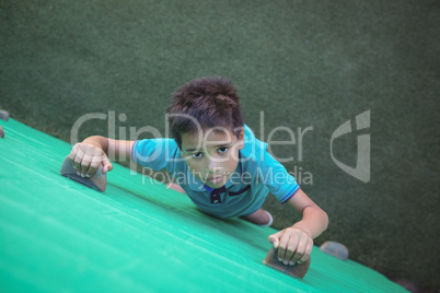Portrait of boy climbing green wall