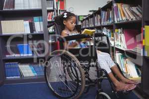 Girl reading book on wheelchair in library