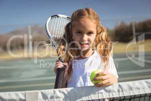 Portrait of girl holding tennis racket and ball