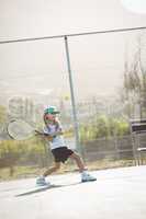 Girl playing tennis against fence