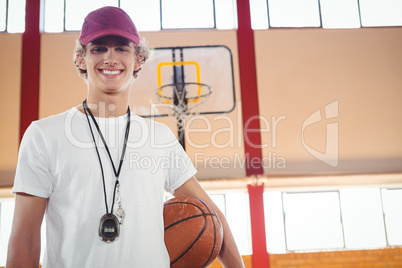 Portrait of male coach standing against basketball hoop