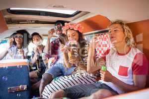 Happy friends blowing bubble wands in camper van