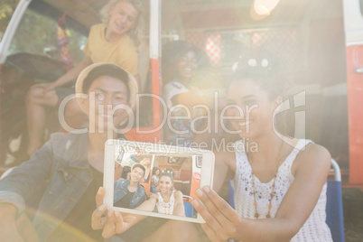 Smiling woman with friends taking selfie at campsite