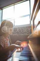 Concentrated girl looking at digital tablet while practicing piano