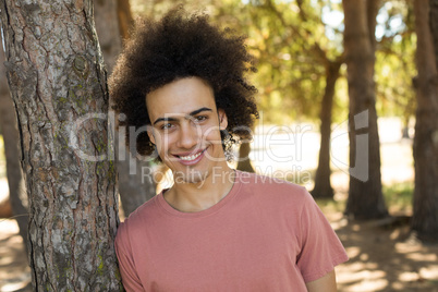 Portrait of man leaning on tree trunk