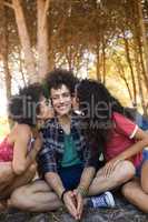 Females kissing young male friends sitting on field