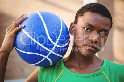 Portrait of teenage boy with basketball on shoulder