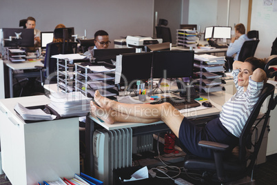 Smiling businesswoman relaxing while colleagues working in office