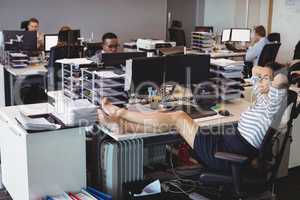 Smiling businesswoman relaxing while colleagues working in office