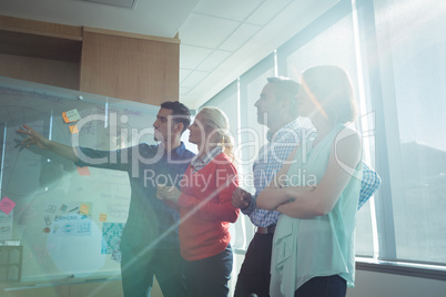 Business colleagues discussing by whiteboard at office