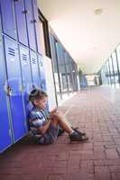 Side view of boy using mobile phone while sitting by lockers