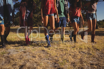 Low section of friends walking on field