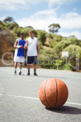 Basketball on ground with player standing in background