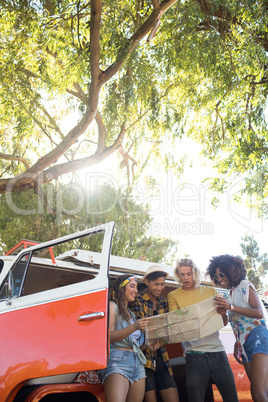 Low angle view of friends reading map at campsite