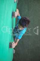 Boy gripping climbing holds on wall