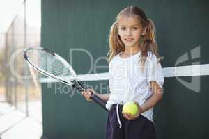 Girl holding tennis racket and ball