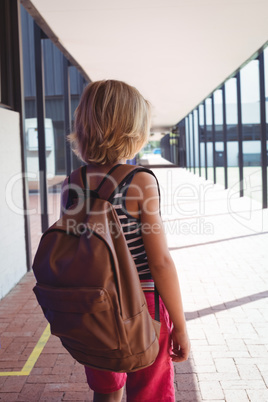 Rear view of schoolboy with backpack standing in corridor