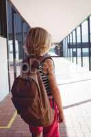Rear view of schoolboy with backpack standing in corridor
