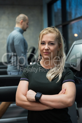 Portrait of woman standing with man exercising on treadmill