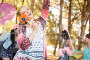 Portrait of happy woman holding pinwheel at campsite