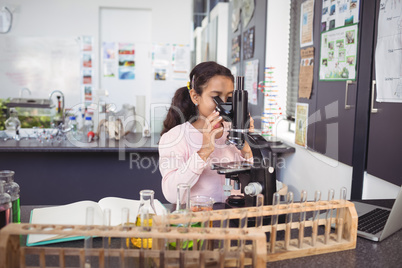 Elementary schoolgirl looking through microscope at laboratory
