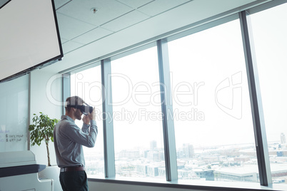 Businessman using virtual reality glasses while standing at office