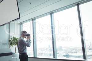 Businessman using virtual reality glasses while standing at office