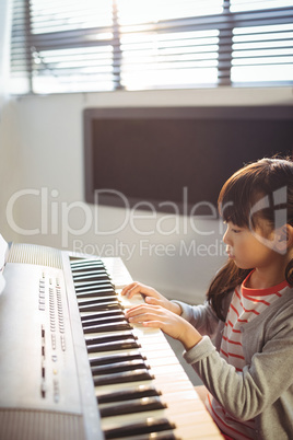 High angle view of concentrated girl practicing piano in class