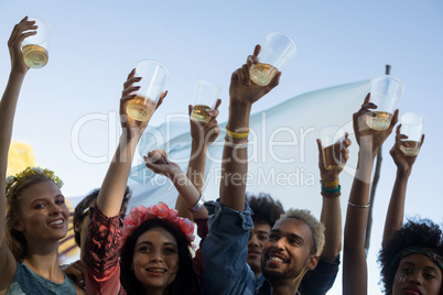 Happy friends holding beer glasses while enjoying music festival