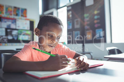 Boy writing in book at desk