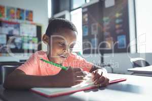Boy writing in book at desk