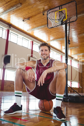 Portrait of basketball player sitting on ball
