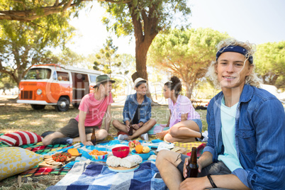 Portrait of smiling man holding drink with friends in background