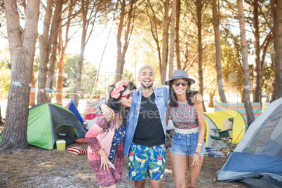 Happy friends standing together at campsite