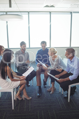 Business people discussing over documents at office