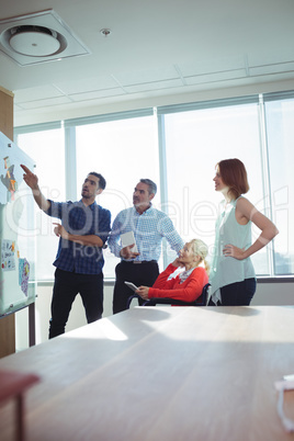 Businessman discussing with colleagues over whiteboard