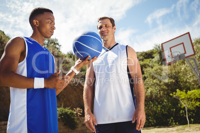Basketball player looking at friend holding basketball