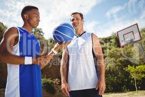 Basketball player looking at friend holding basketball