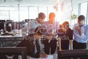 Businesswoman drawing on paper while working with team