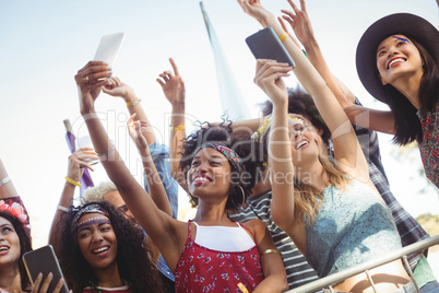 Low angle view of friends taking selfie through their mobile phones at music festival